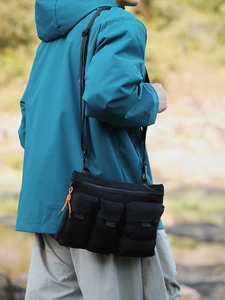 Outdoor tactical black crossbody bag with three front pockets and orange zipper pulls