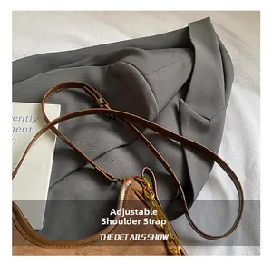 Detail of adjustable leather strap and gold chain on brown suede crossbody bag