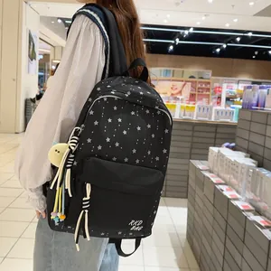 Detail of black backpack with white star patterns and yellow plush ball charm on side