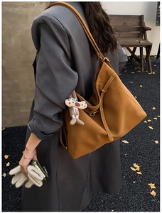 Detailed shot of brown faux leather tote with adjustable strap and plush charm accent