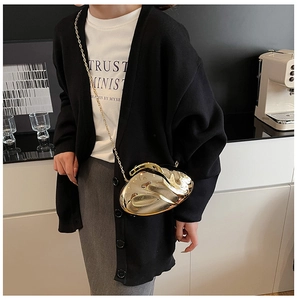 Close-up of a gold irregular acrylic clutch bag with a fluid mirror finish and chain