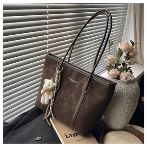 Detail of dark brown matte tote bag with teddy bear pendant and fashion leather print