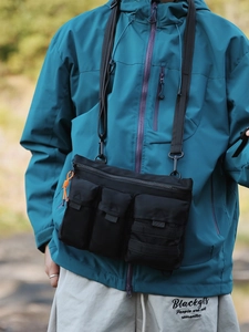 Outdoor tactical crossbody bag in black nylon with three front pockets and orange zipper detail