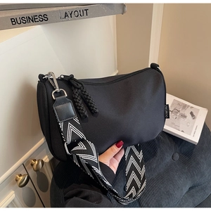 Detail of black nylon pillow bag showing adjustable geometric patterned wide shoulder strap