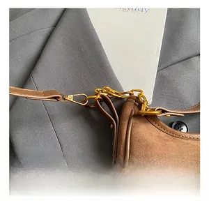 Detail of golden metal hook and stitching on brown suede underarm shoulder bag