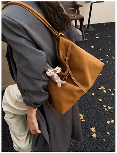 Brown leather tote bag featuring golden hardware and a cute puppy charm in street style