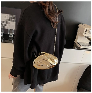 Close-up of a gold shell-shaped acrylic evening clutch bag with a metallic chain strap