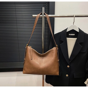 Close-up of brown PU leather tote bag featuring brand logo and vertical stitching details
