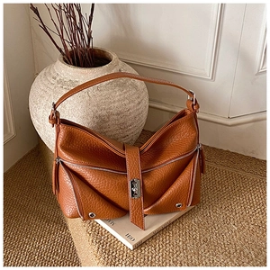 Detailed macro view of the brown lychee pattern leather and silver zipper on the tote bag