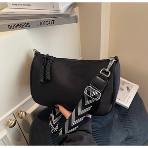 Close-up of black nylon half-moon bag with geometric patterned wide strap and zipper detail