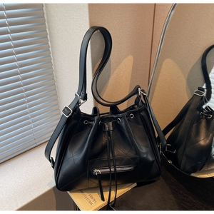 Détail du sac seau noir matelassé avec fermeture à cordon et poche zippée à l'avant