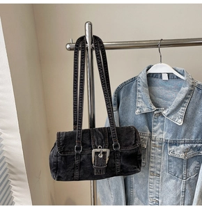 Détail d'un sac Boston vintage en denim noir avec boucle métallique sur un cintre