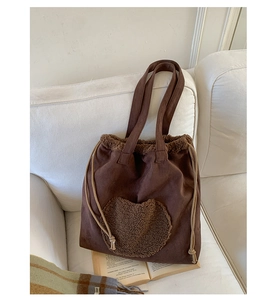 Detail of vintage brown tote bag with plush heart patch and drawstring closure