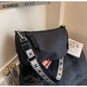 Detail of black nylon dumpling bag featuring a wide geometric patterned shoulder strap