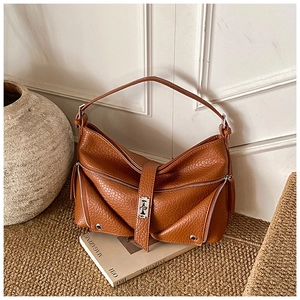 Detail of brown litchi pattern leather shoulder bag with zipper trim and buckle closure