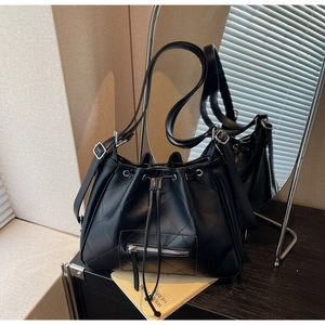 Détail du sac seau matelassé noir avec cordon de serrage et zip argenté sur bois
