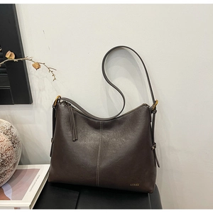 Detail of vintage brown leather tote bag with gold metal logo and fine stitching accents