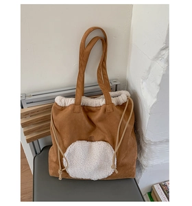 Close-up of brown suede tote bag with white fleece trim and drawstring closure