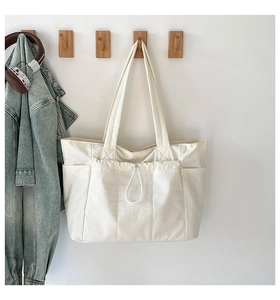Détail du sac fourre-tout en toile blanc cassé avec poche avant à cordon et compartiments