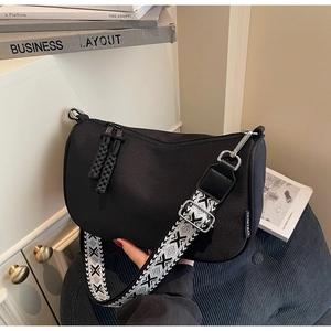 Detail of black canvas crescent bag featuring geometric patterned wide shoulder strap