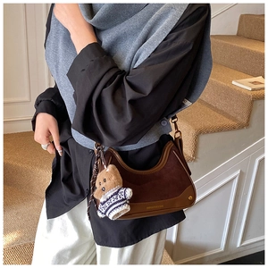 Detail of vintage brown suede shoulder bag with a cute striped teddy bear pendant