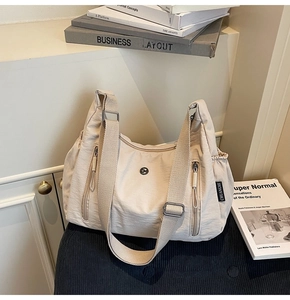 Détail du grand sac à bandoulière en nylon avec sangle réglable et poches zippées multiples