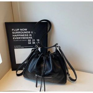 Détail d'un sac seau matelassé noir avec cordon de serrage et poche frontale zippée