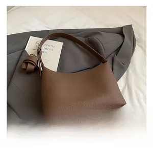 Detail of dark brown lychee leather tote with a stylish decorative knot charm and wide strap