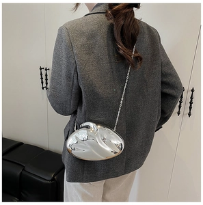 Polished silver abstract metal evening bag with chain strap on a blazer outfit