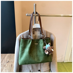 Detail of green suede tote bag with diamond lattice pattern and cute bear charm