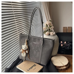 Detail of dark grey tote bag with fashion text and cute white teddy bear charm