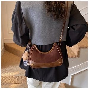 Detail view of a vintage brown crossbody bag featuring mixed suede and leather textures