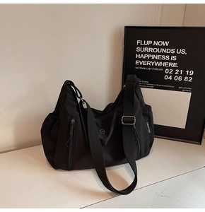 Détail montrant la texture en nylon noir imperméable et les poches zippées de ce sac à main