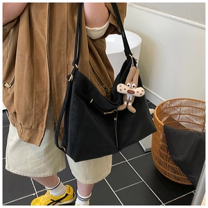 Black matte tote bag detail with adjustable straps and a cute plush animal charm