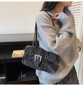 Détail du sac bandoulière en denim vintage avec boucle argentée et coutures contrastées