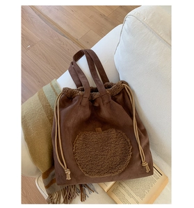 Detail of soft brown faux suede tote with large fuzzy apple patch and drawstring detail