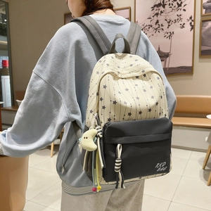 Detail shot of the beige star pattern and dark gray front pocket on a large school backpack