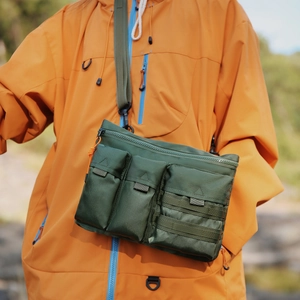 Détail du sac bandoulière d'extérieur vert avec poches multiples et système de sangle MOLLE