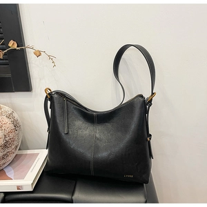 Detail of black faux leather tote bag with white contrast stitching and gold zipper