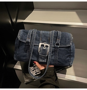Détail du sac à épaule en denim bleu foncé avec une boucle argentée sur le rabat frontal