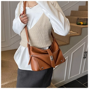 Detail of caramel textured leather shoulder bag featuring silver zippers and turn-lock