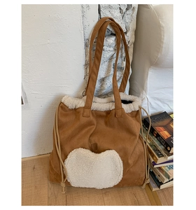 Detail of a brown faux suede tote bag with a white fuzzy heart and adjustable drawstring