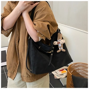 Detail of black Hobo tote bag with golden hardware and cute brown bunny plush charm