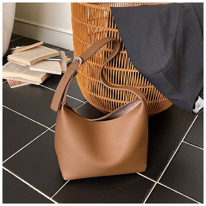 Detail view of brown pebbled leather hobo tote bag with silver buckle in vintage home setting