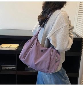 Détail du sac bandoulière en nylon violet avec plusieurs poches et étiquette tissée de marque