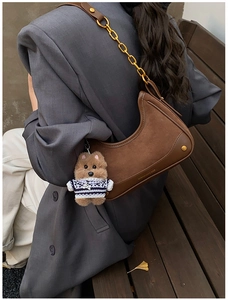 Close-up of vintage brown leather crescent bag with chain strap and puppy charm