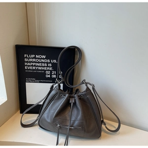 Détail du sac seau matelassé taupe montrant le cordon et la texture fine du cuir