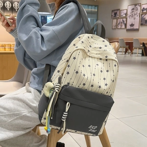 Detailed view of canvas star pattern backpack with plush charm in a cozy indoor setting