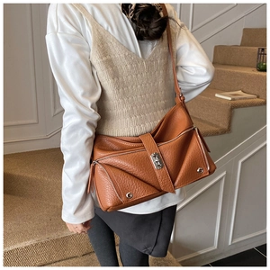 Detailed shot of brown pebbled leather shoulder bag with silver turn-lock and 'G' hardware