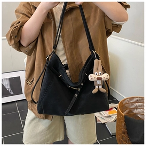 Detail shot of a black matte leather Hobo bag with a plush squirrel charm and metal buckle